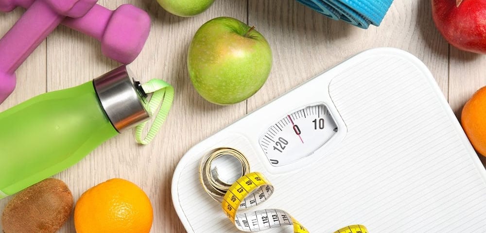 healthy foods, work out equipment, and scale with measuring tape