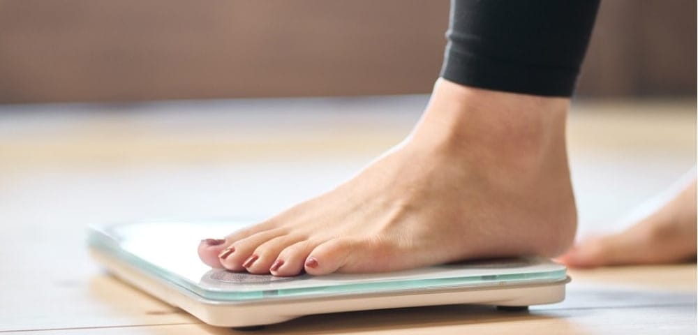 Woman weighing herself on scale