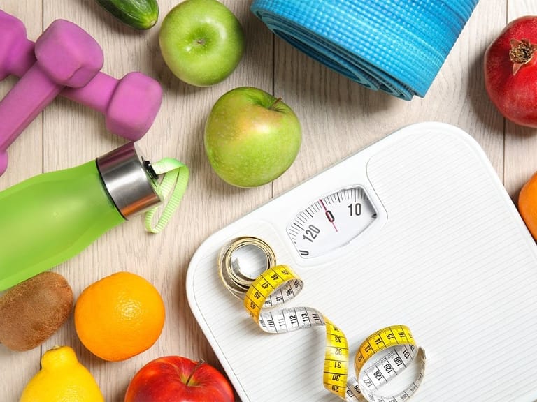 healthy foods, work out equipment, and scale with measuring tape