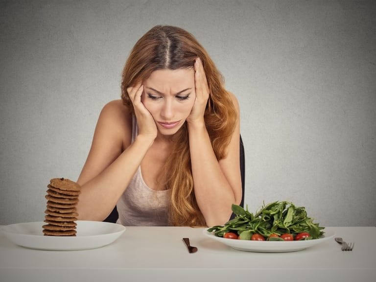 woman struggling with weight loss goals before learning how to control food cravings