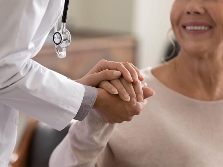 close up of concierge doctor holding a smiling patient's hand