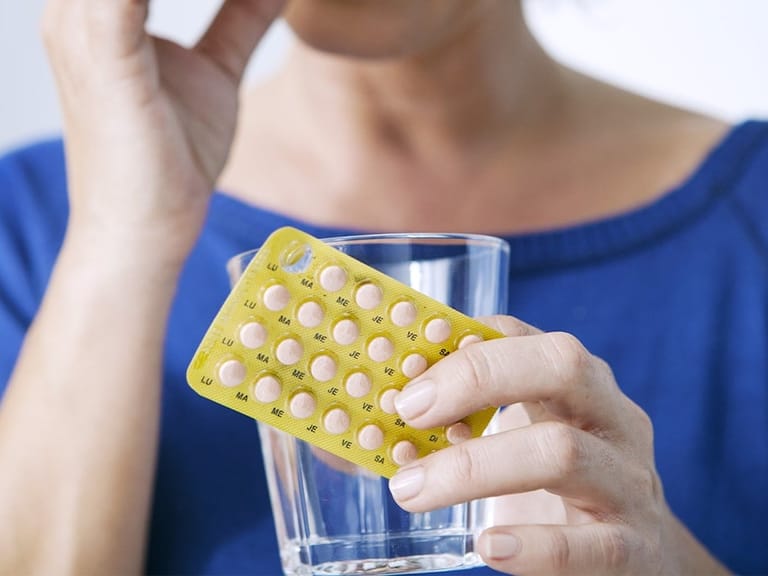 woman taking bioidentical hormone replacement therapy pills