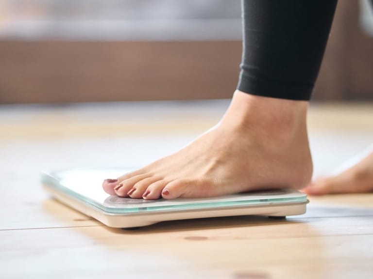 Woman weighing herself on scale