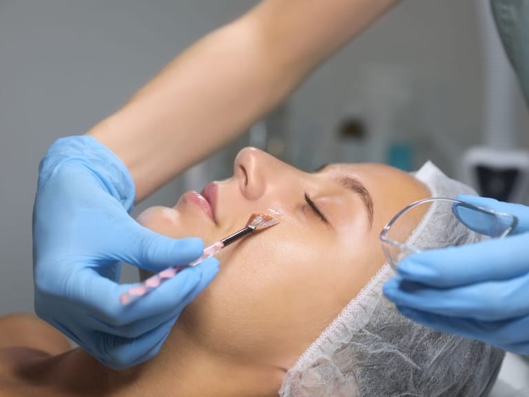 doctor applying chemical peel to woman's face