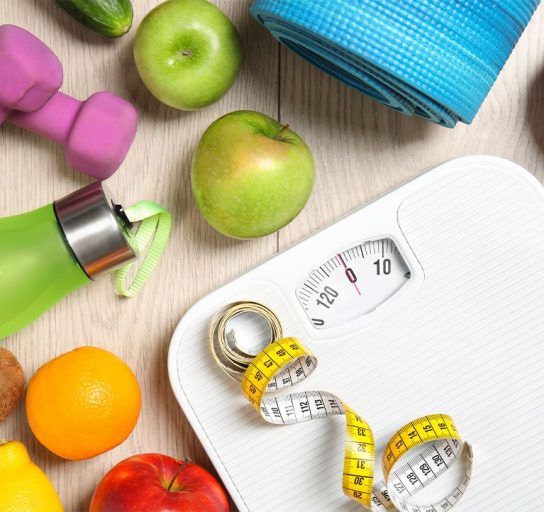 healthy foods, work out equipment, and scale with measuring tape