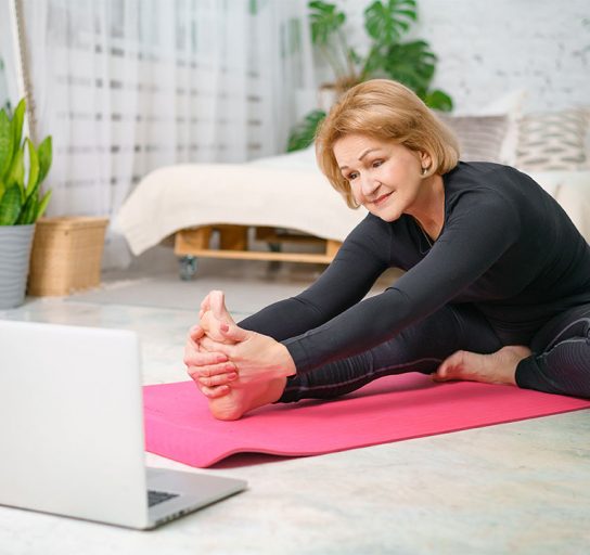 older woman stretching on yoga mat before exercise